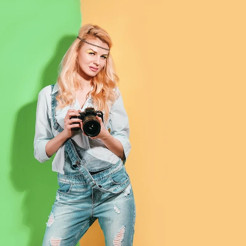 Fotograf kobieta robi zdjęcia na jasnym tle w słoneczny dzień